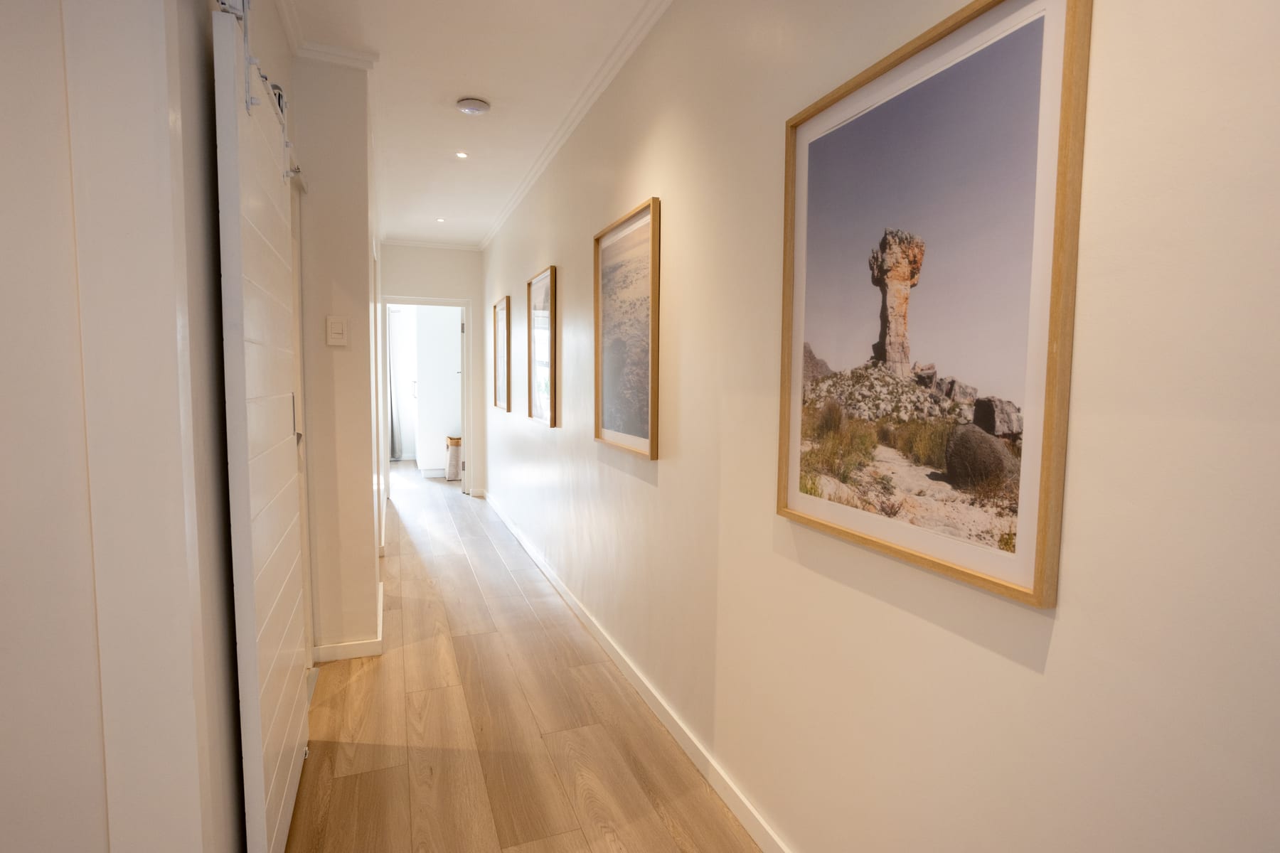 Renovated hallway with light flooring and framed South African photographs
